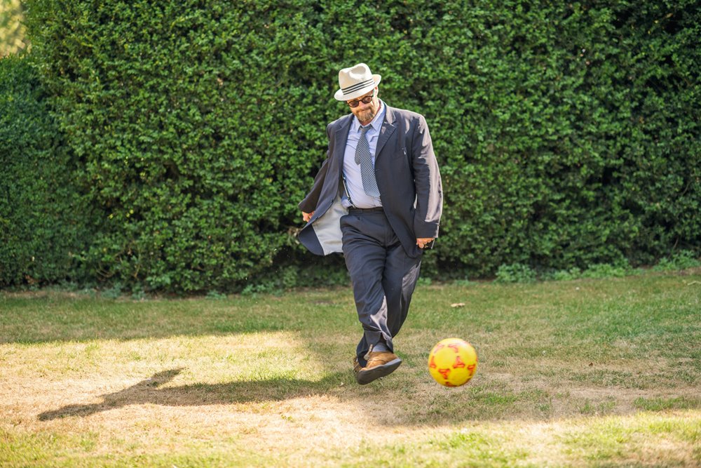 Guest relaxedly kicking a ball in the grounds at garden party wedding