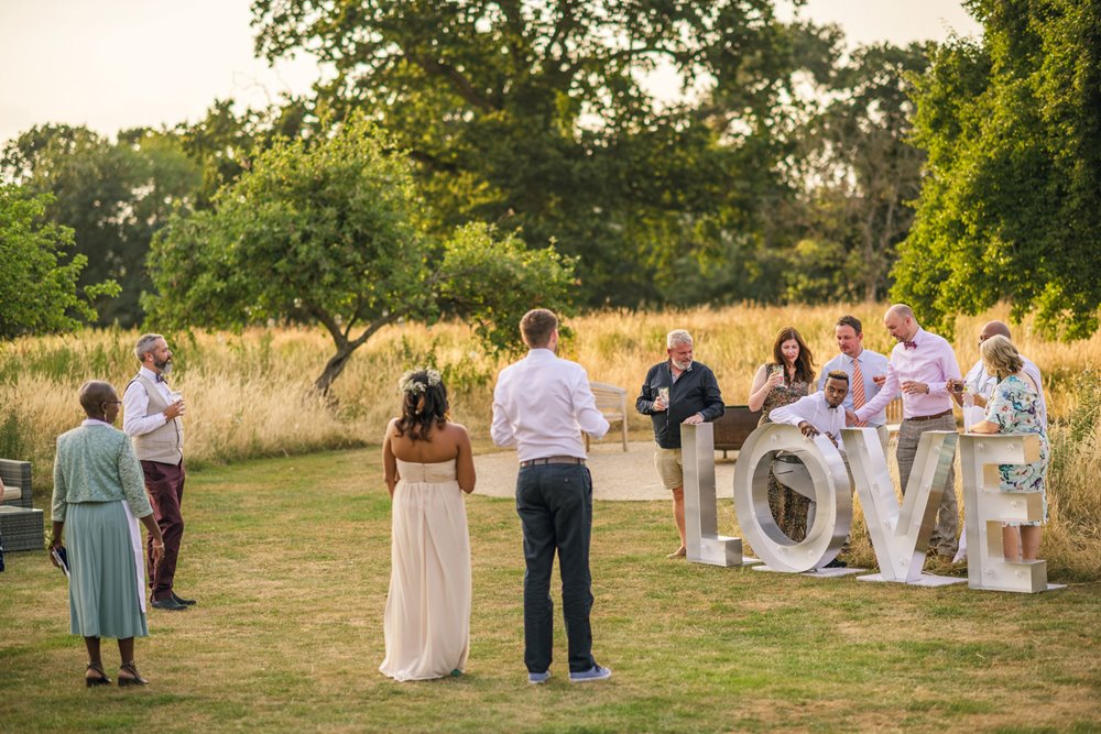 Love is love! Sign with guests posing at gay wedding in the cotswolds countryside