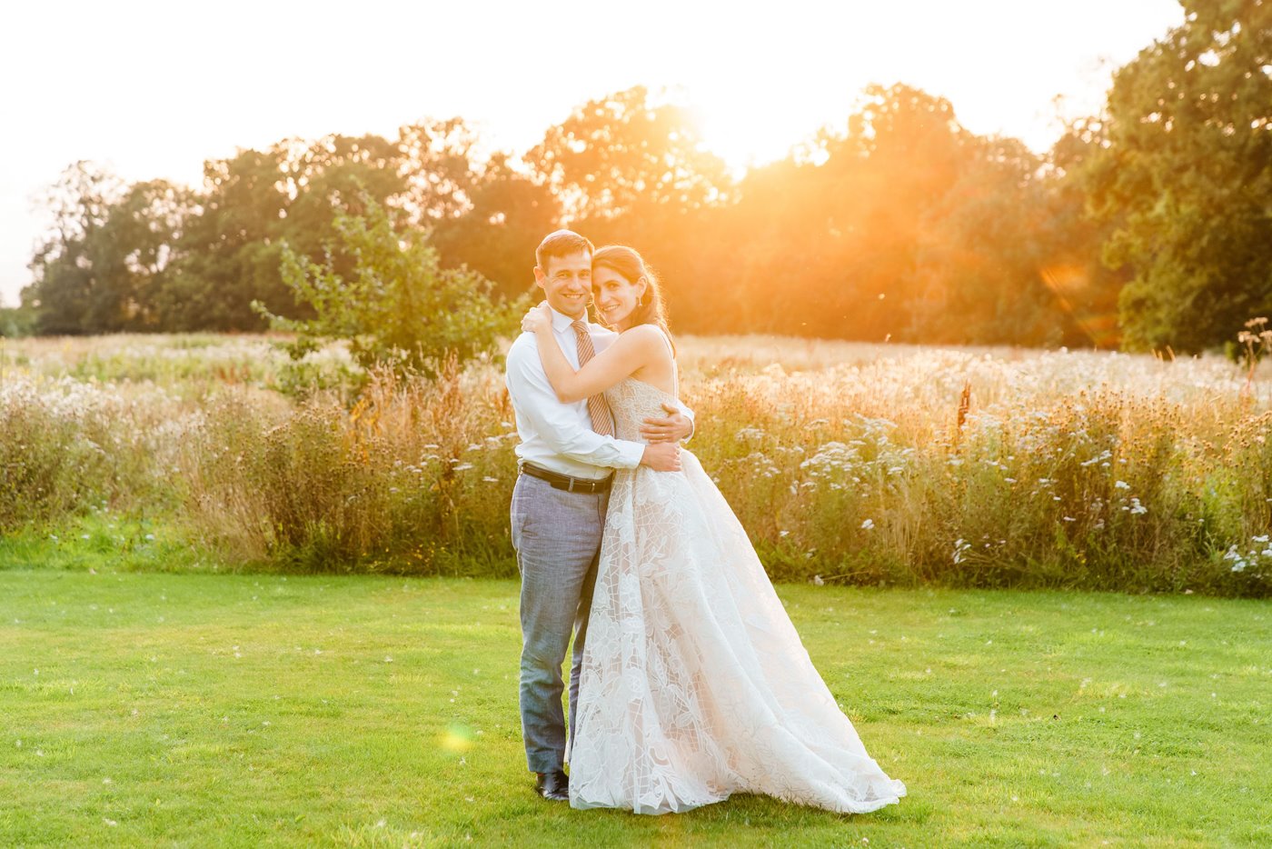 Happily newlywed couple posing in the sunset in the Gillyflower meadow at elmore court