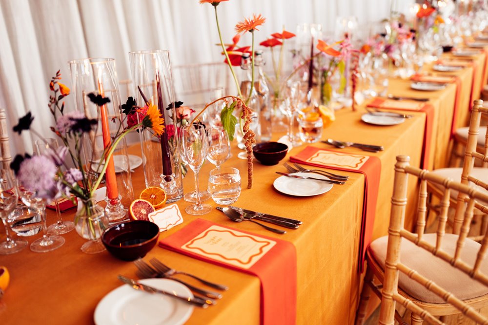 Colourful wedding flowers on orange table for bright reception in the cotswolds