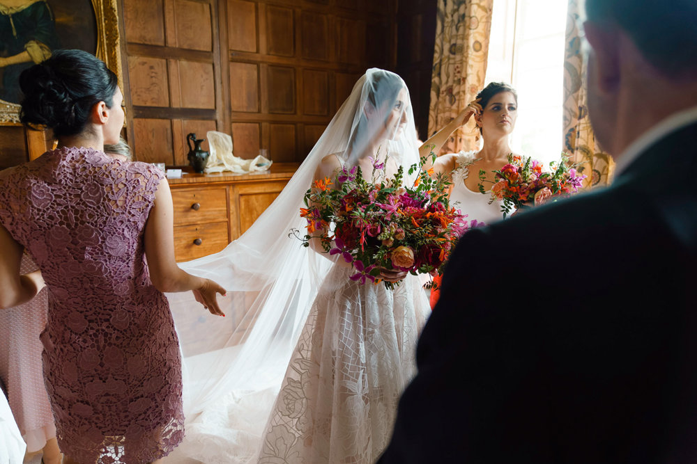 Veiled bride holds huge bright pink and orange statement bouquet of flowers at her bedeken jewish wedding
