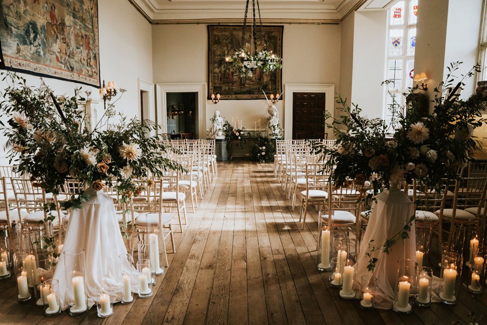 Romantic wedding ceremony with candles and florals in the hall of stately home wedding venue elmore court for a lgbtq wedding with two brides 