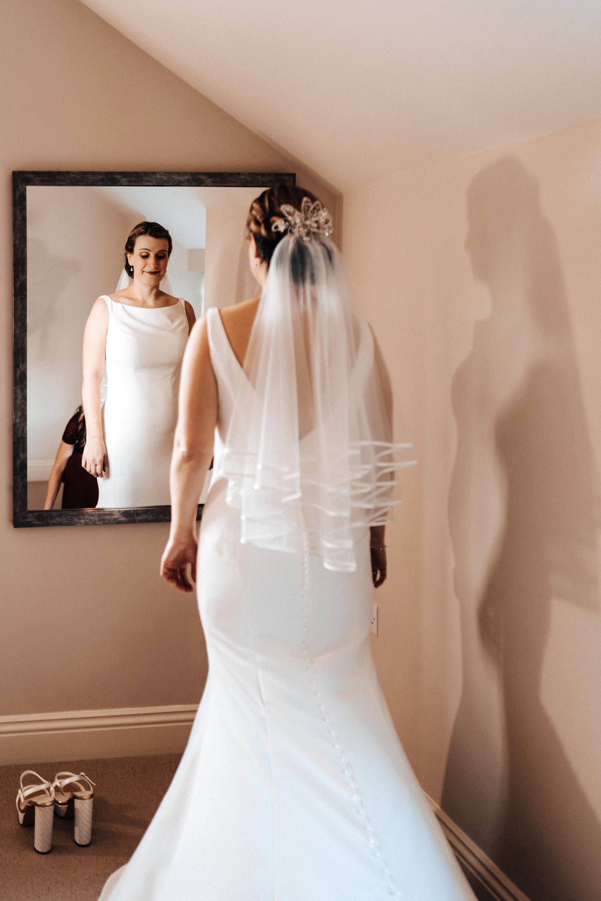 Pregnant bride looking in mirror on christmas wedding morning wearing elegant dress