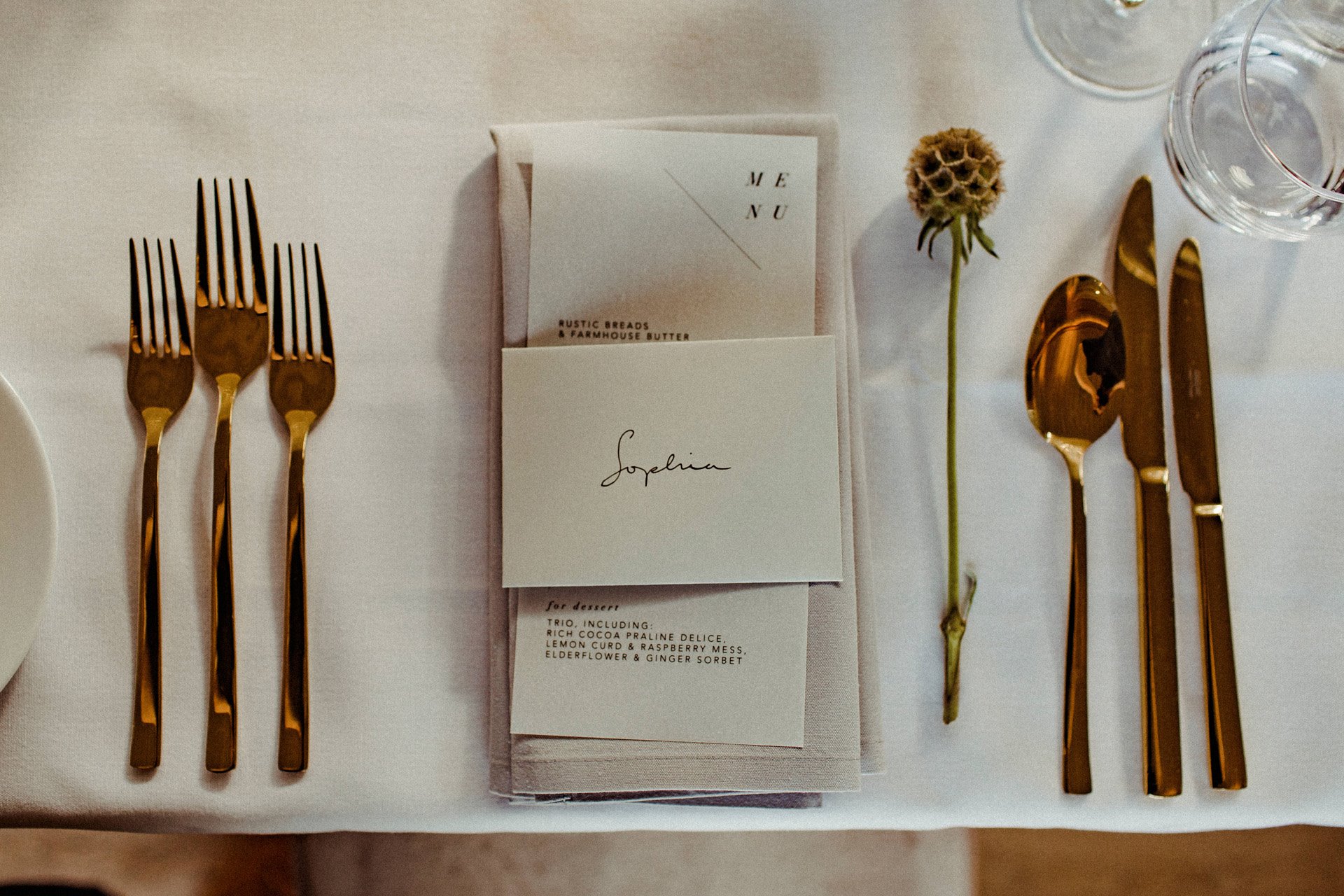 Beautiful minimalist wedding table place setting with gold cutlery for a modern autumnal wedding