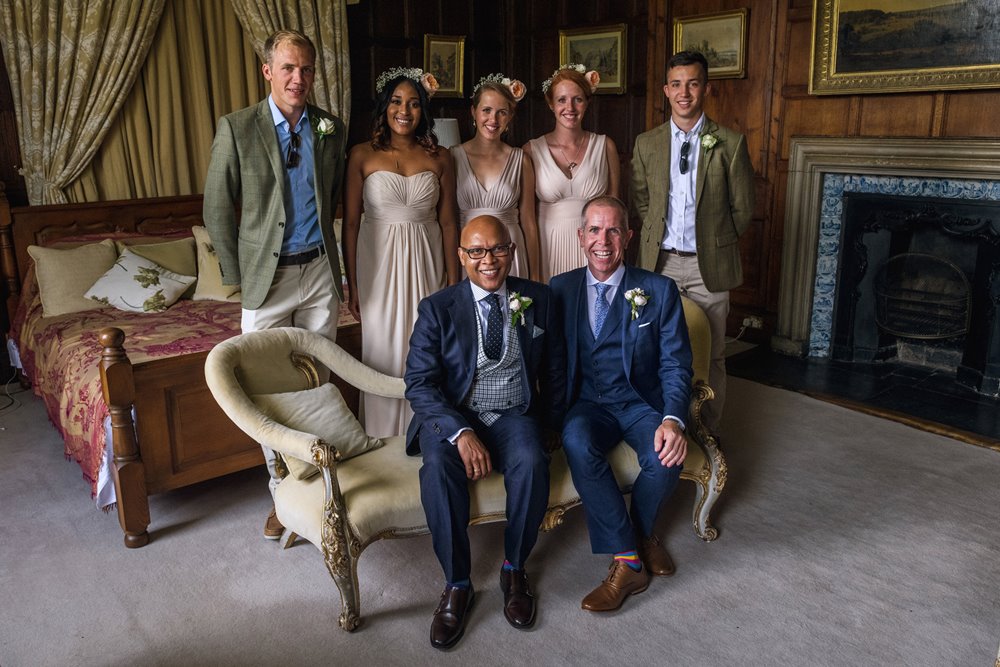 Grooms pose with their wedding party in the master suite