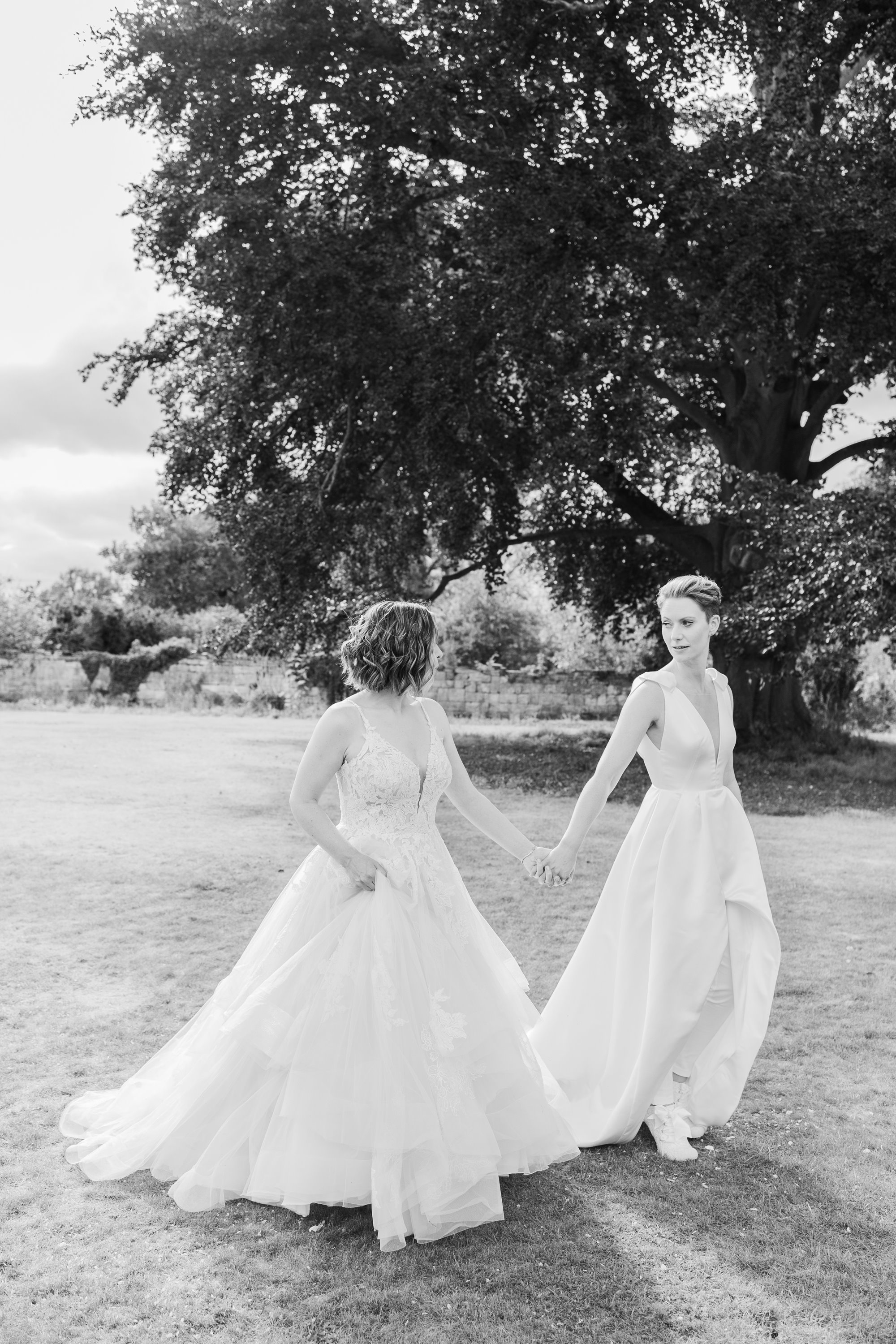 two brides holding hands and staring into each others eyes on a beautiful summer day
