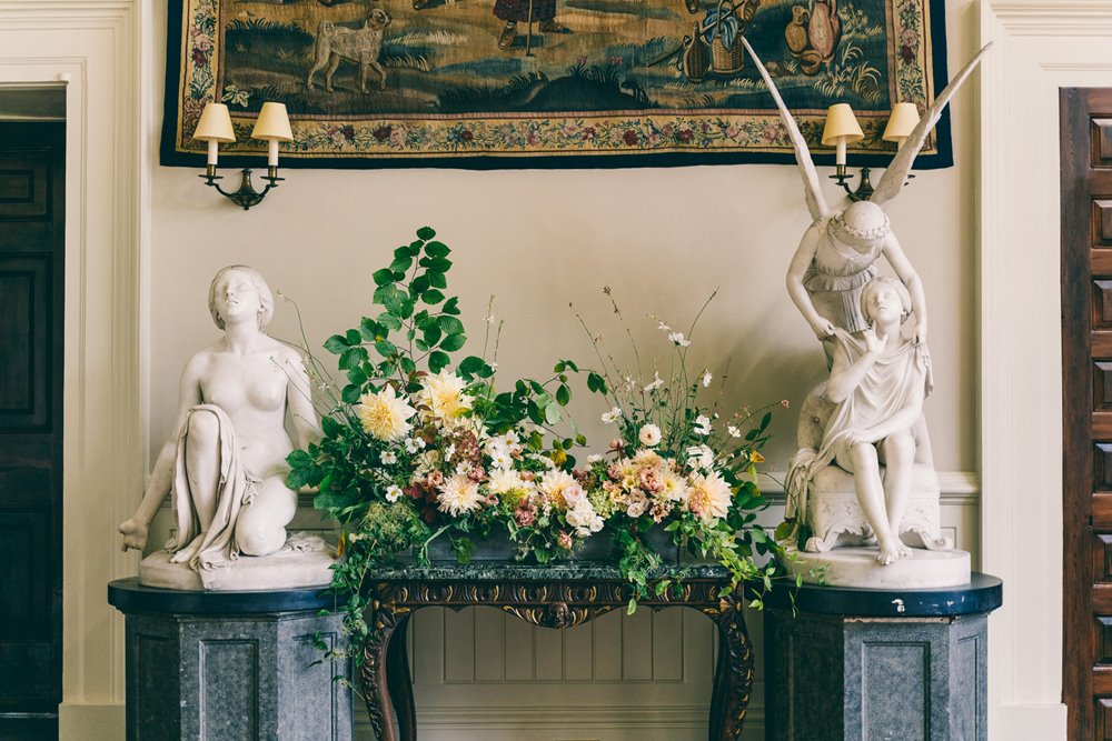 Beautiful Wedding flowers arranged by angel statues at the end of the aisle for a micro wedding at Elmore Court