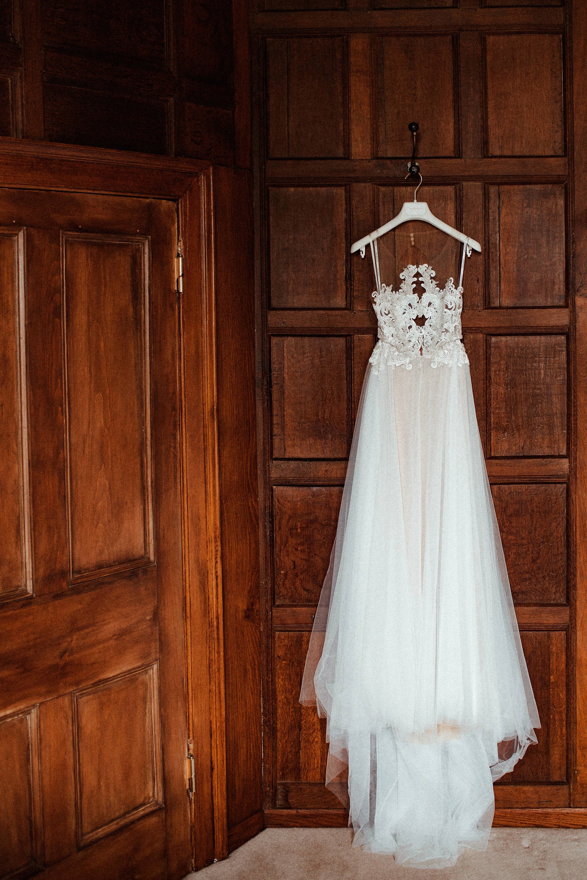 Liz Martinez pre raphaelite gown hanging on wood panelled wall of stately home elmore court 