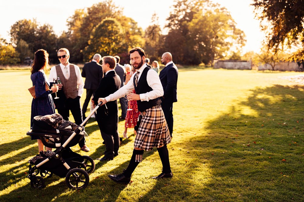 Wedding guest in kilt pushing baby in pram