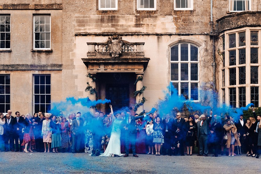 Blue smoke bombs for a surprise gender reveal at this winter wedding with pregnant bride at stately home in the cotswolds