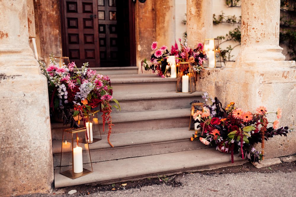 colourful wedding flowers and candles on the steps of mansion house wedding venue in gloucestershire