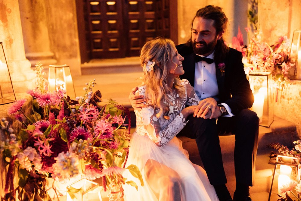 cool bride and groom with colourful wedding flowers and candles on the steps of mansion house wedding venue in gloucestershire