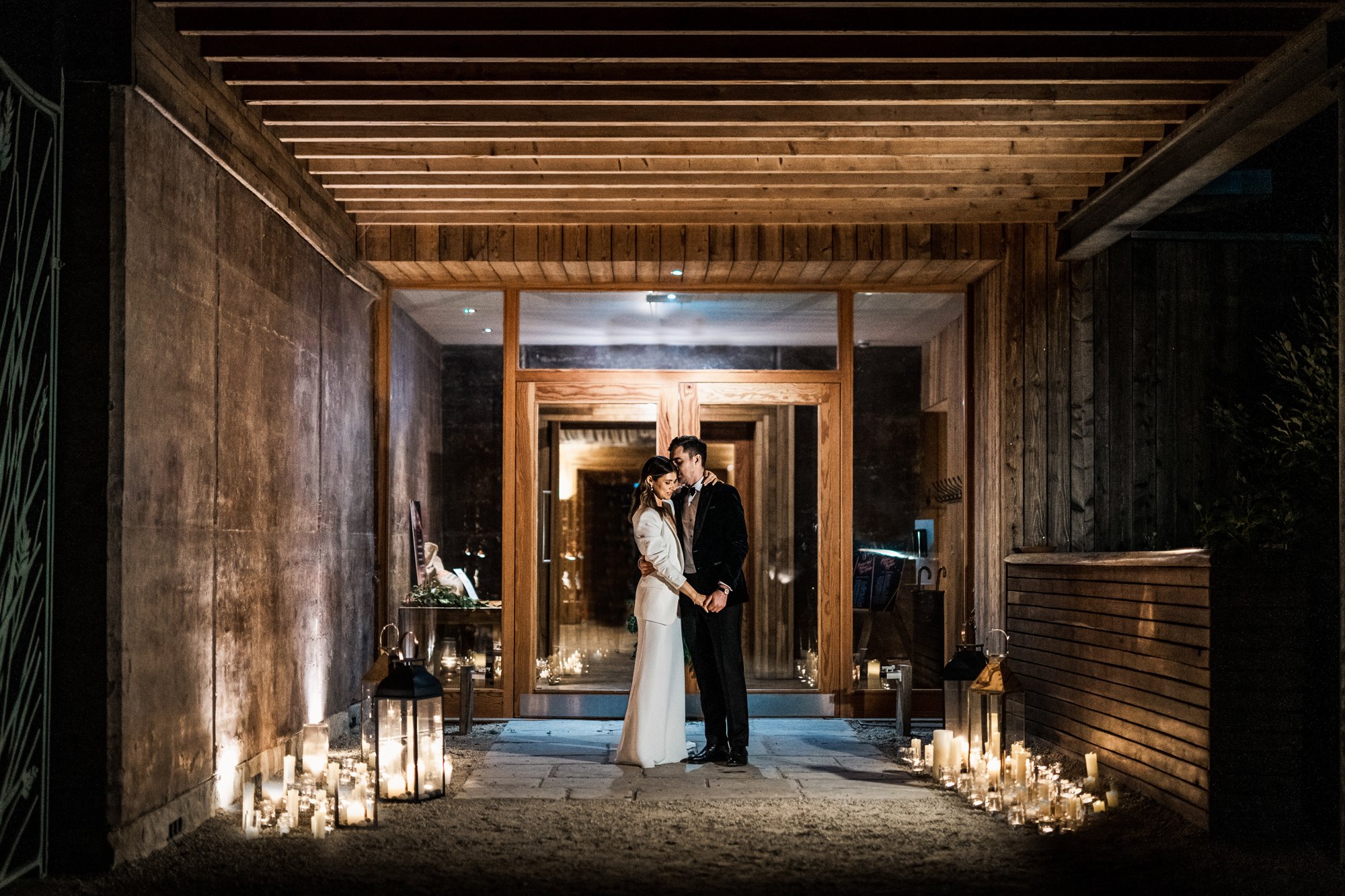 bride and groom embracing while they are surrounded by displays of softly glowing candles