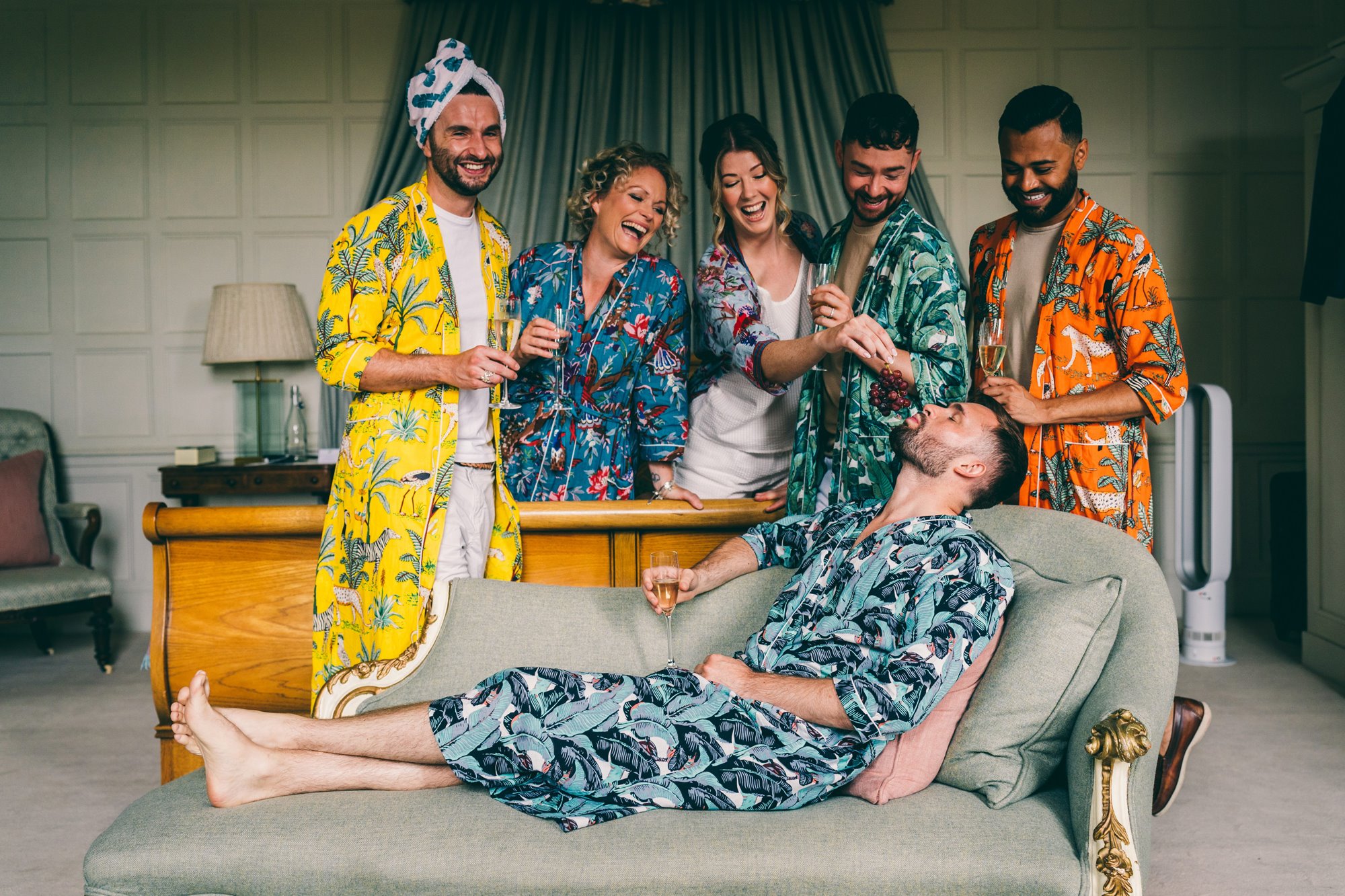 grooms party wearing funky dressing gowns on the morning of the grooms wedding, all drinking champagne
