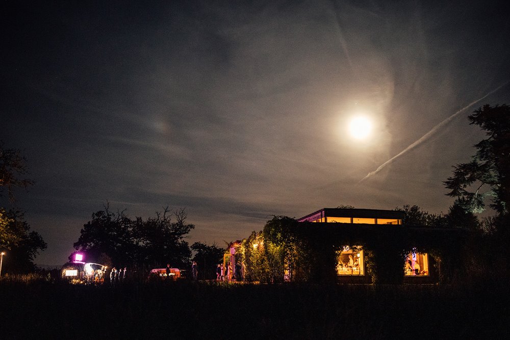 Cool silver trailer caravan photo booth with pink neon lights and bunting at unusual wedding venue elmore court