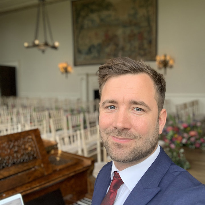 Wedding pianist sitting at piano in beautiful stately home wedding venue in the uk