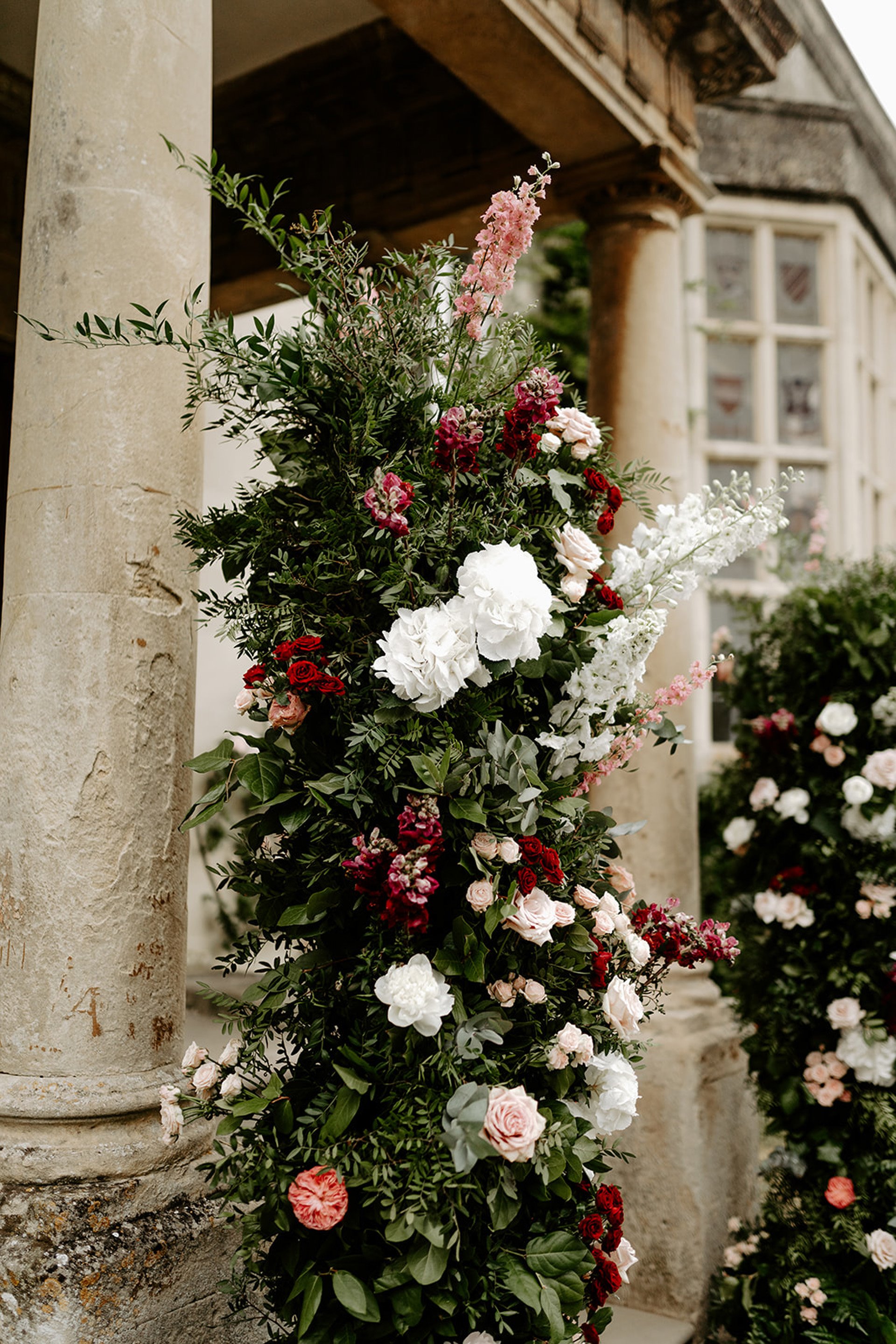 Romantic wedding flowers decorating entrance columns of old stately home wedding venue
