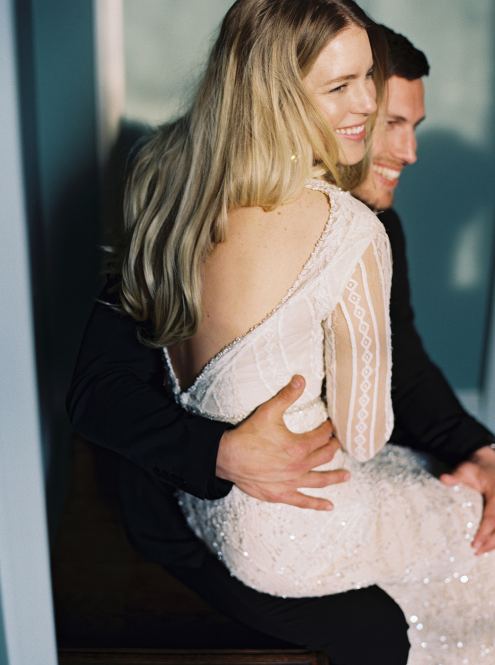 Beautiful bride sitting on her husbands lap as they pose for their wedding photographs