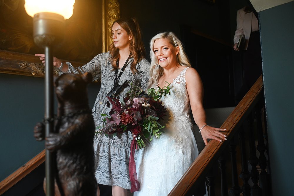 october bride walking down stairs of stately home wedding venue at her autumnal wedding