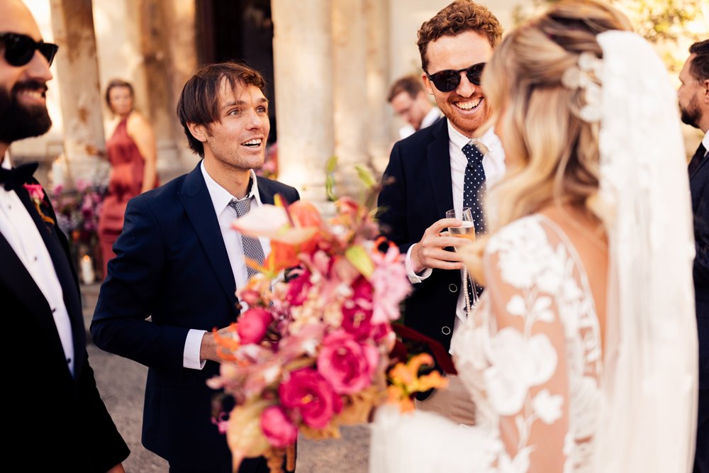 Colourful wedding flowers and cool bride and groom in sunny drinks reception outside elmore court