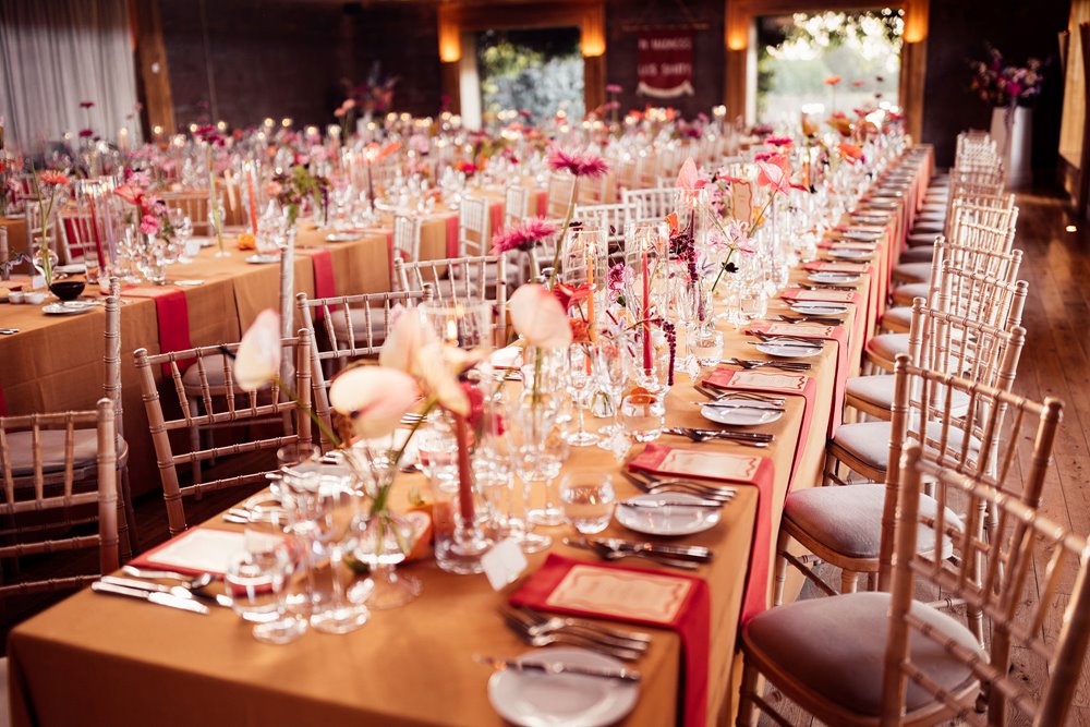 Modern Colourful wedding theme. Orange tables with fruit and flowers at sustainable wedding venue in the cotswolds