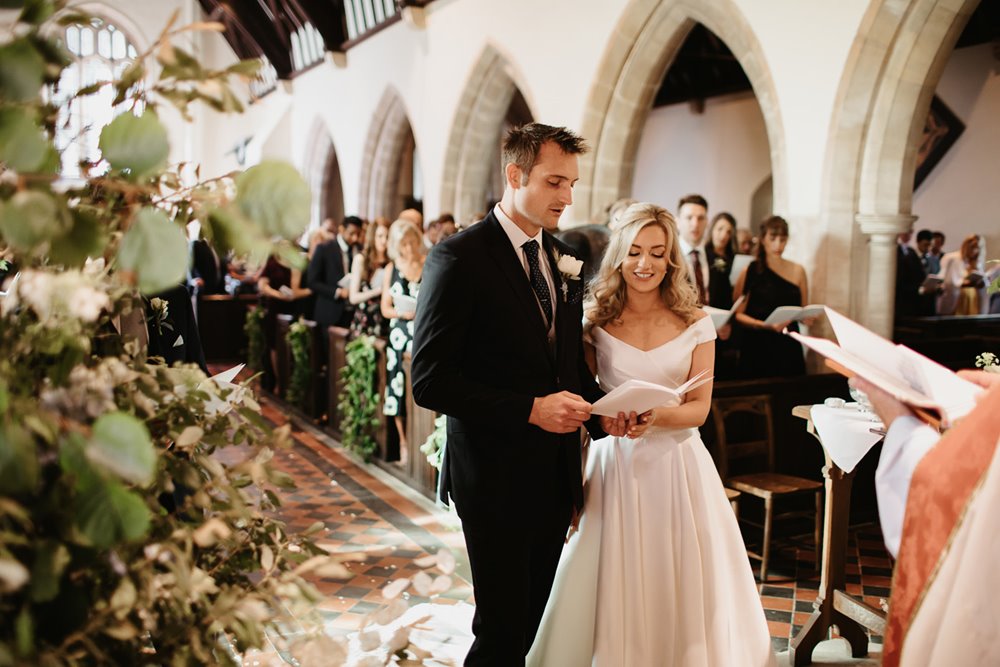 Couple hold hands to sing hymn as part of wedding service in the church