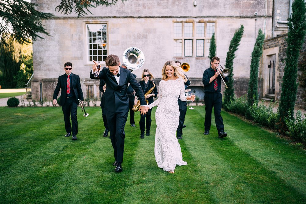 newly wed bride and groom dancing to a brass band on a beautiful lawn at Elmore Court