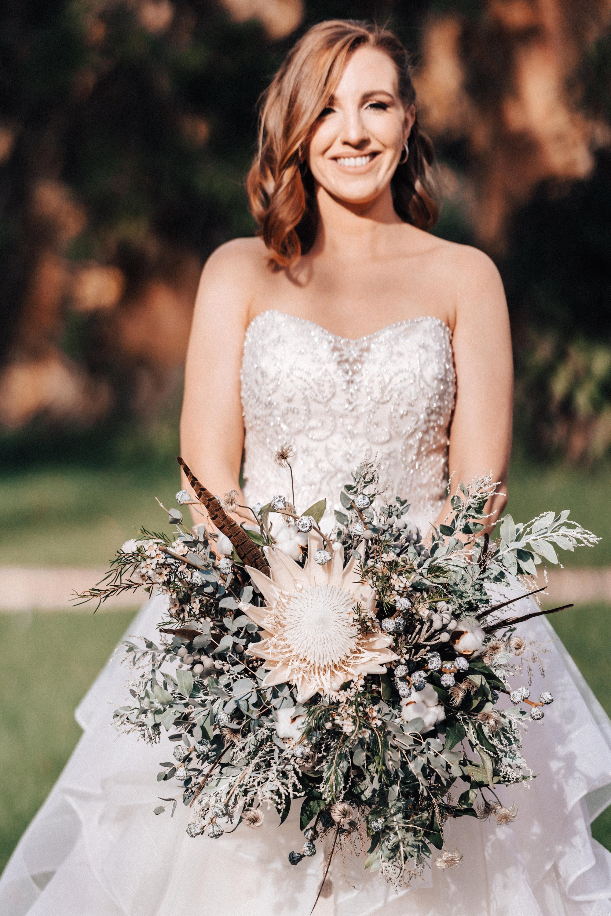 bride in pearl and lace bodice dress holding thistle wild bouquet