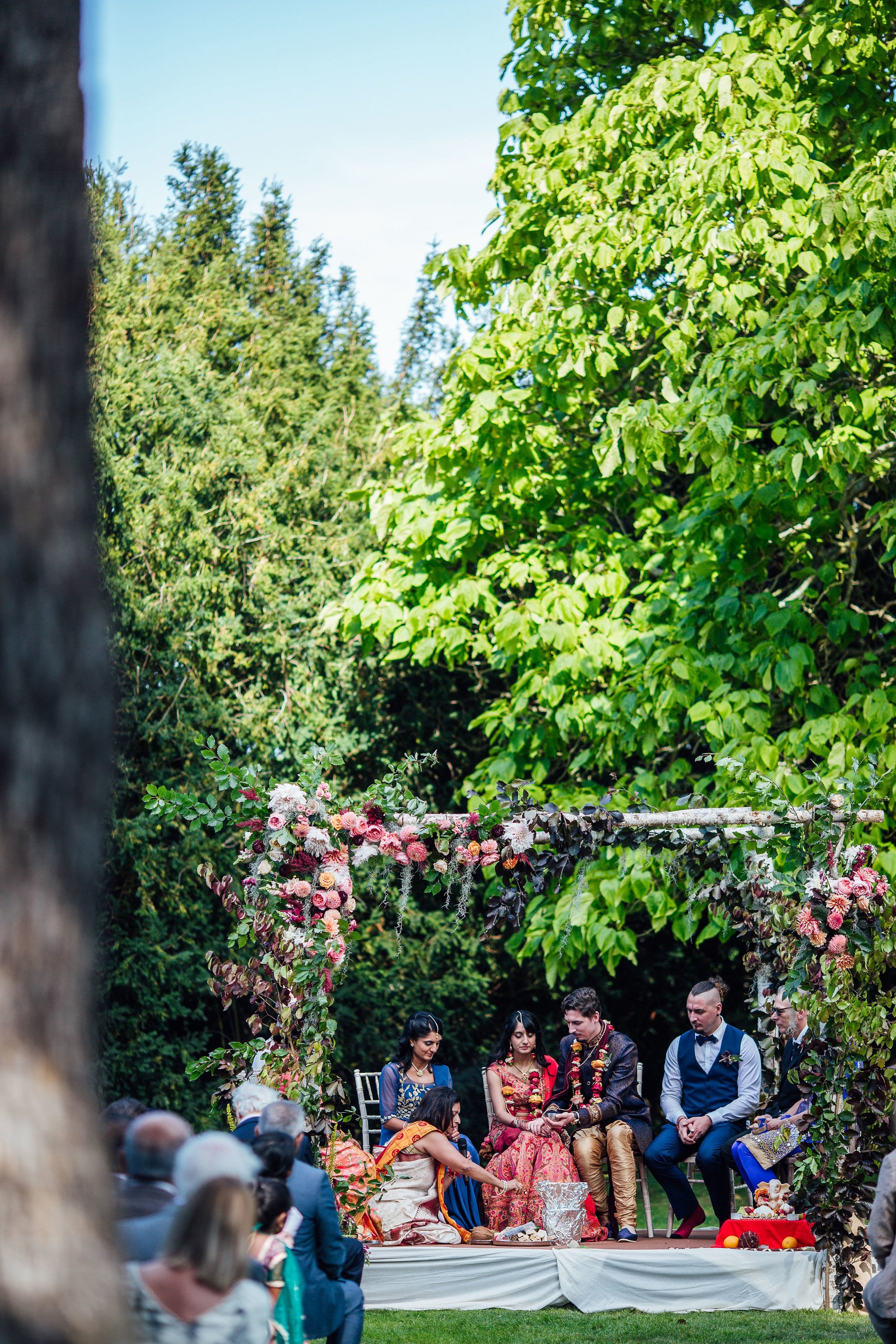 Indian wedding ceremony outdoors in a mandap decorated with pink and red roses