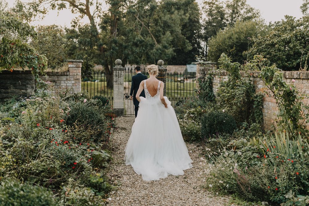 Bride and groom walking towards the walled garden on their wedding day at manor house elmore court
