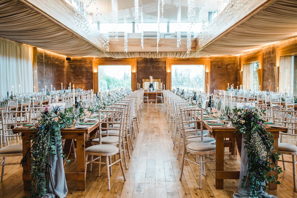 Big wedding reception with long tables and greenery and candles for day 2 of an epic weekend wedding