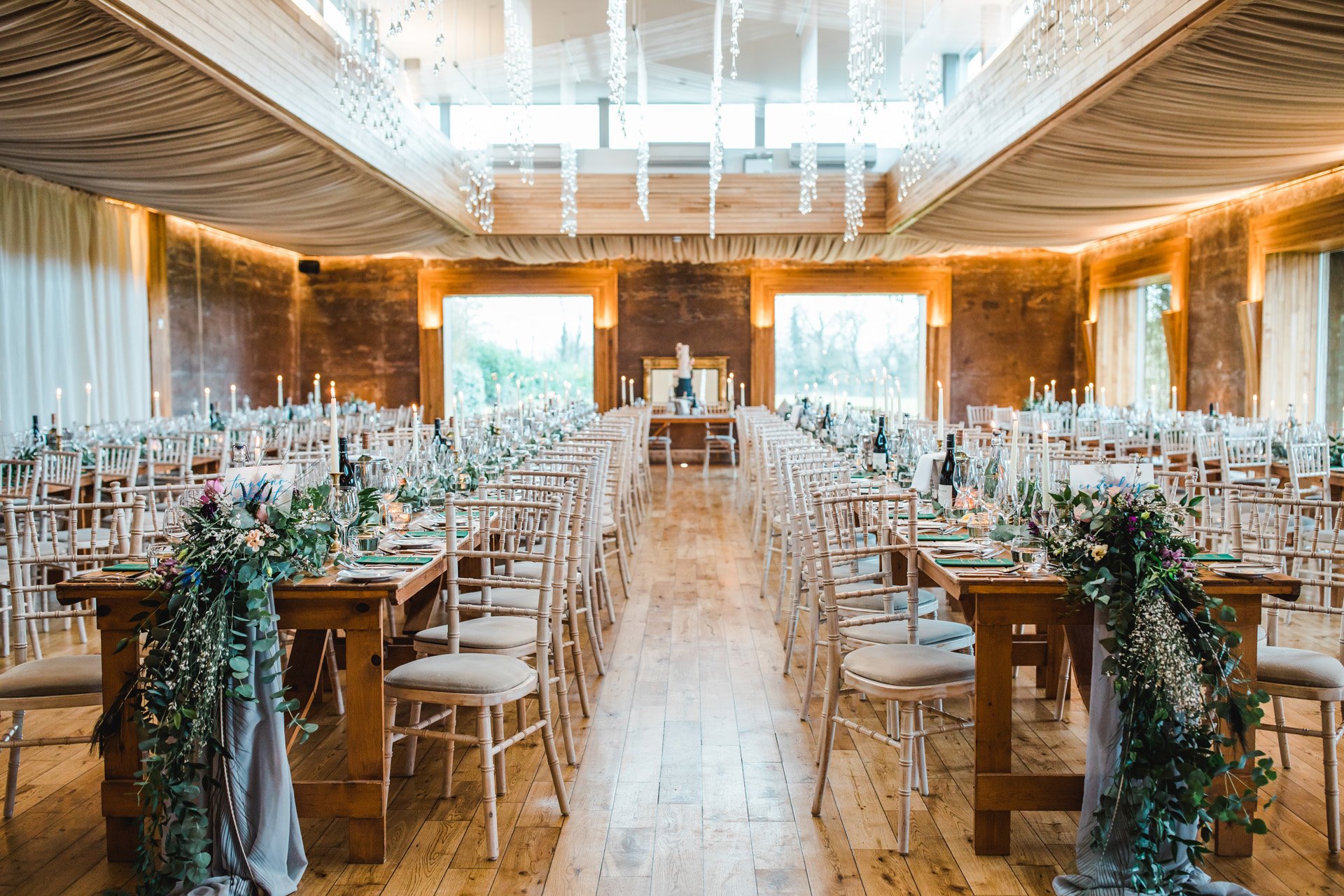 Big wedding reception with long tables and greenery and candles for day 2 of an epic weekend wedding