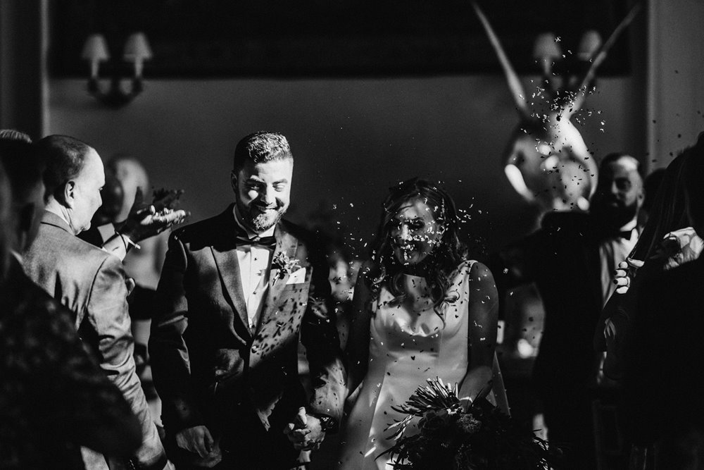 black and white photo of confetti throwing at a dark and moody wedding ceremony in october in old country house