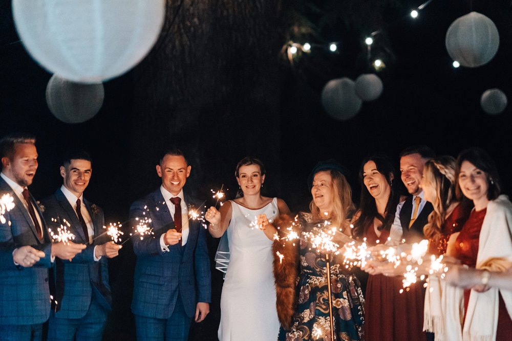 bridesmaids and groomsmen with sparklers at christmas wedding