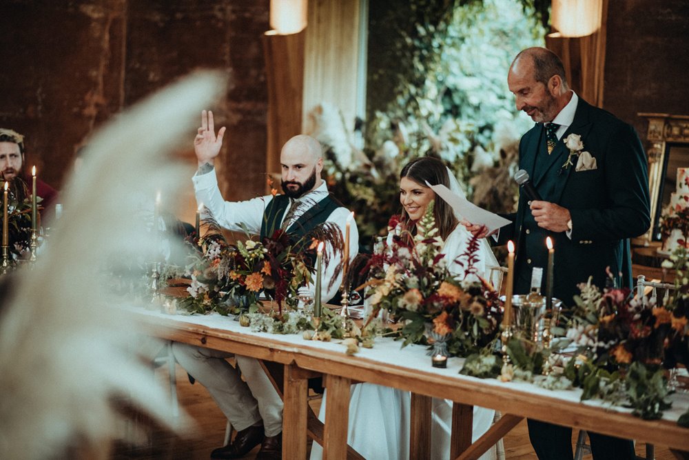 Modern rock wedding reception with rustic dark florals and pampas in the cotswolds