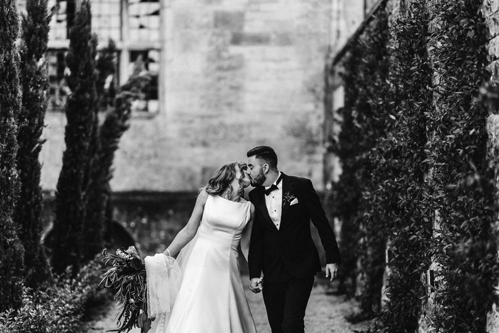 black tie bride and groom kiss in black and white photo of autumn wedding at elmore court