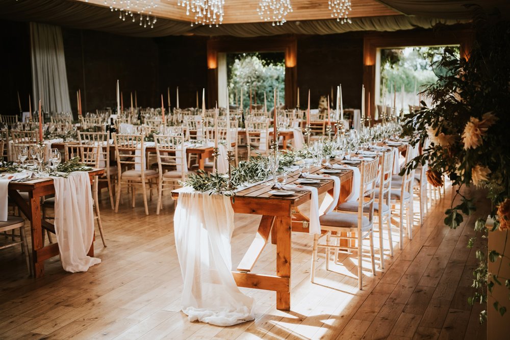 Romantic tables draped with linen and decorated with greenery and elegant candles in a beautiful light and airy wedding venue in Gloucester