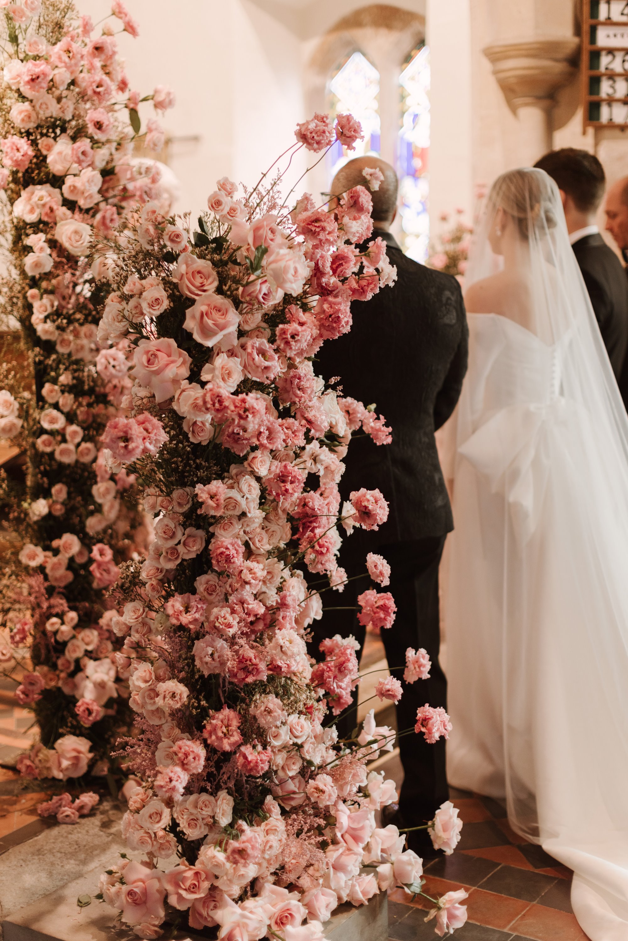 Large pink flower display next to the aisle of a couple getting married