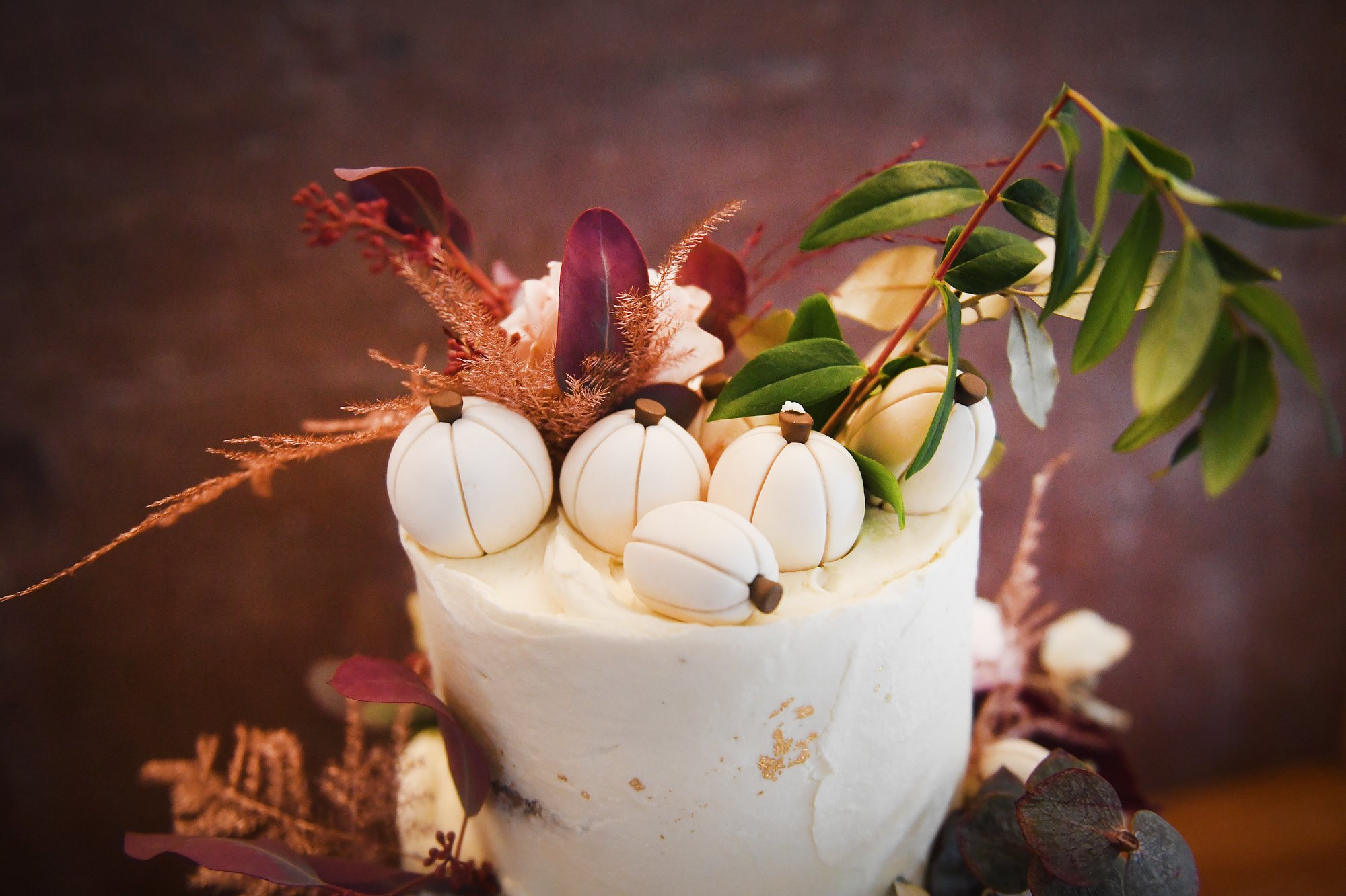 Pumpkin wedding cake decorated with mini fondant pumpkins and autumnal foliage for an october wedding