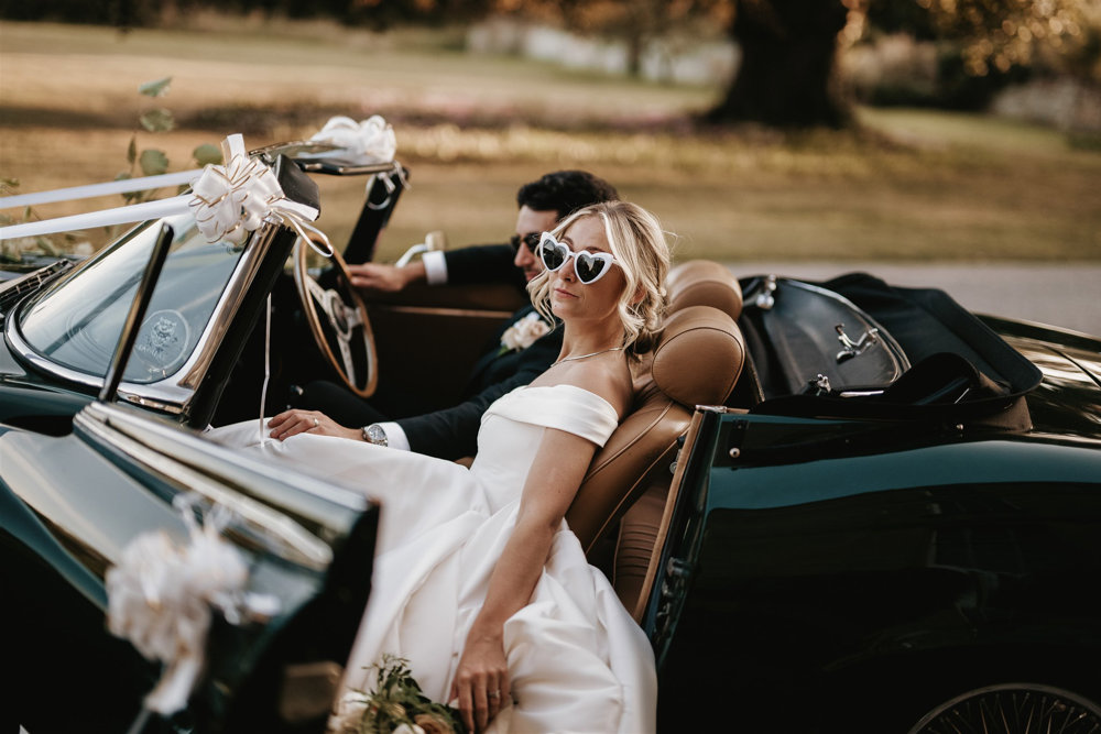 Bride and groom chilling in a convertible car