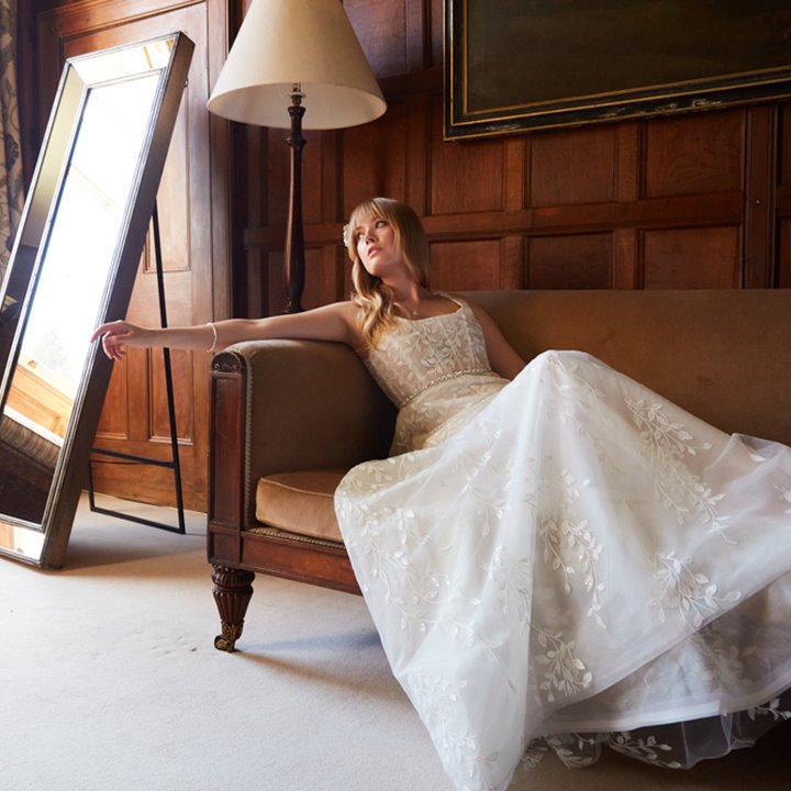Bride in Sustainable wedding dress reclining on a sofa in a historic wood panelled bedroom of sustainable mansion house wedding venue elmore court in Gloucestershire