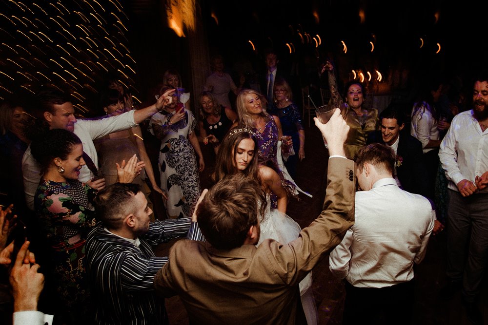 Blurry guests having an amazing party wedding dancing round bride and groom in the UK