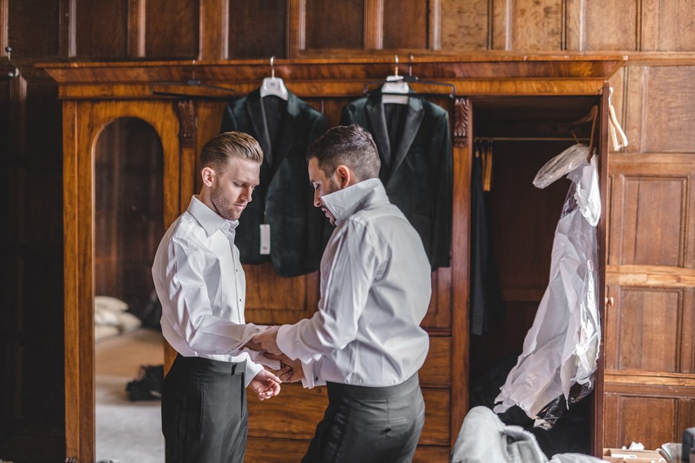 Two grooms helping each other get ready for their wedding day