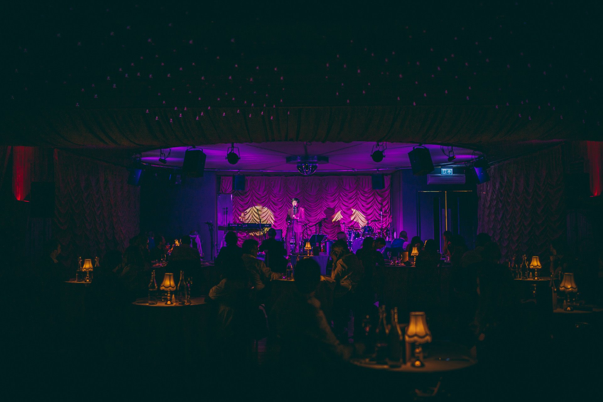 Marcel Lucont stand up comedian in a purple suit under purple lights at cabaret dinner show