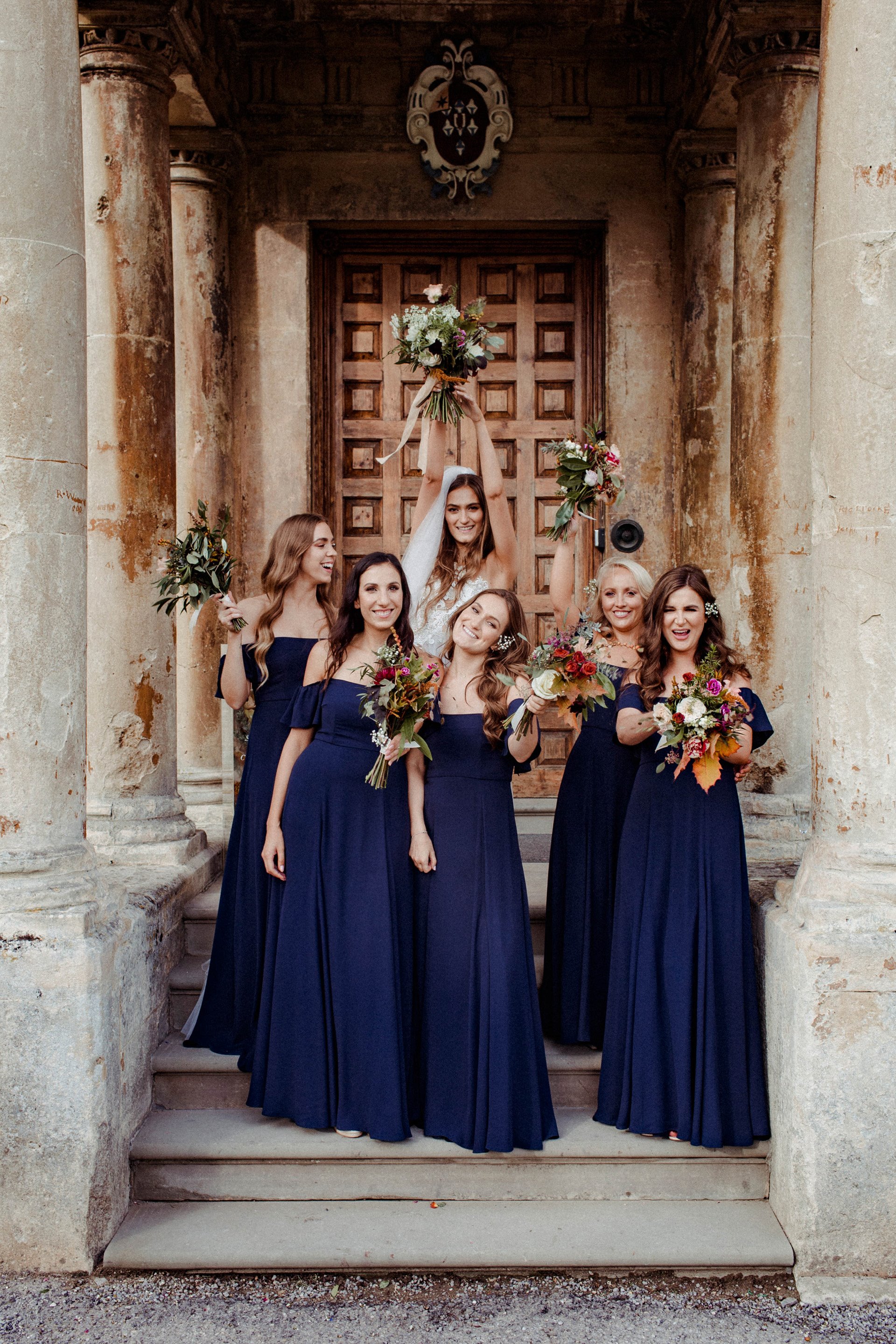 Bridal party on steps of mansion house wedding venue holding autumnal bouquets