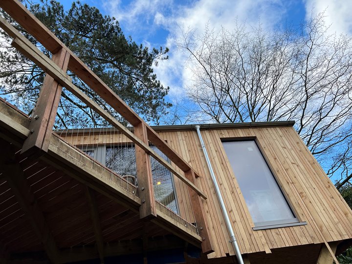 Woodland treehouse against a beautiful blue sky with trees in the background