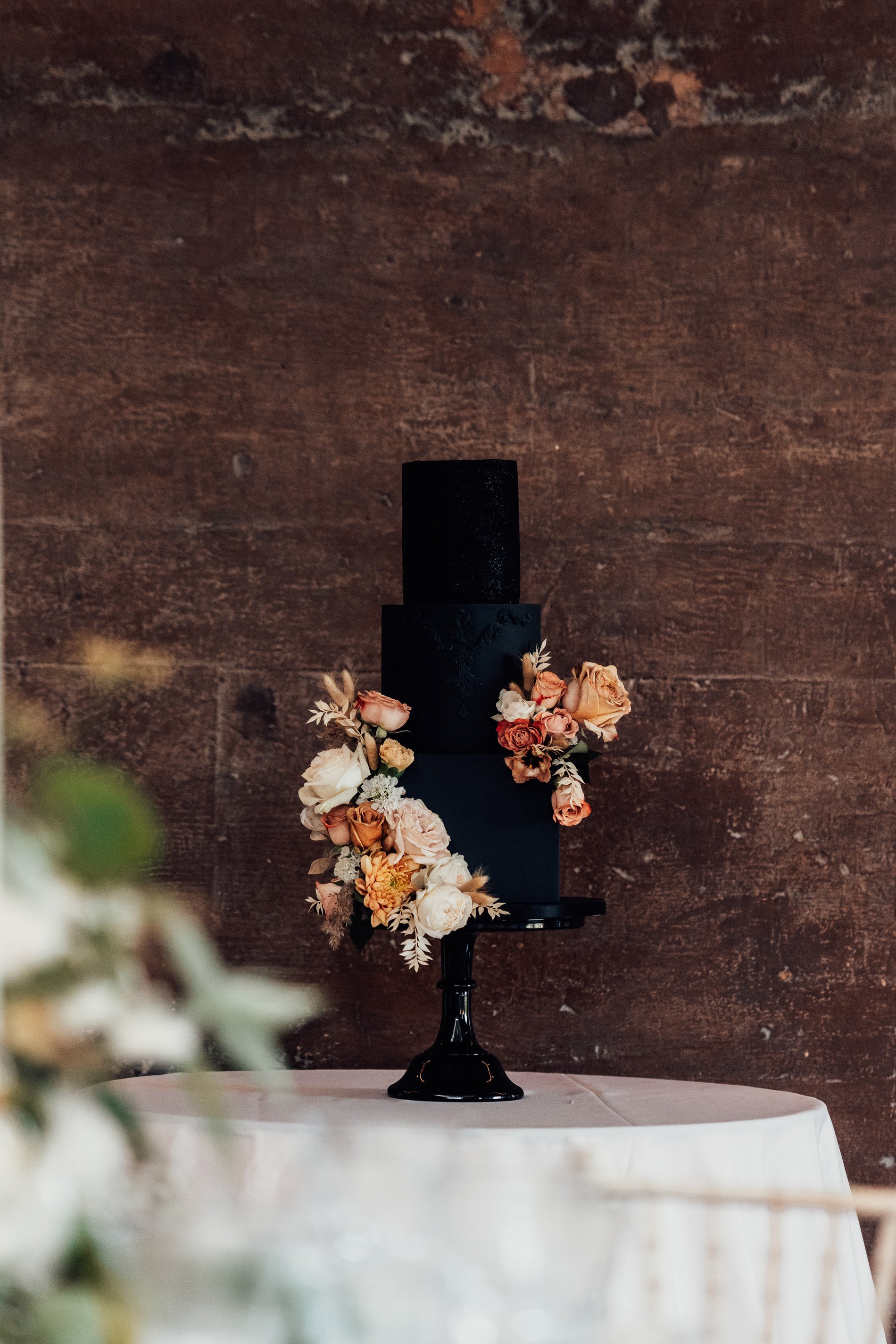 Black wedding cake with 3 tiers decorated with pretty yellow and white flowers