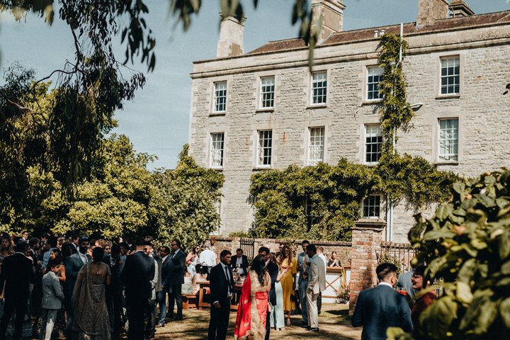 a summer wedding in the walled garden of stately home wedding venue elmore court. Guests relaxed and enjoy the dappled sunshine at drinks reception in the orchard