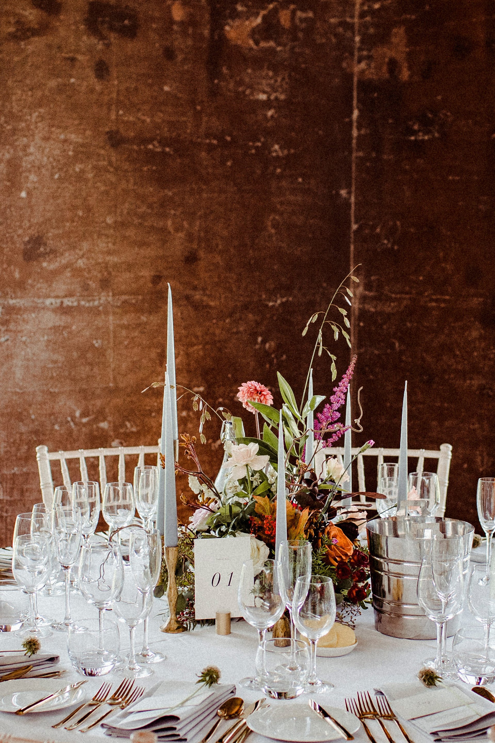 Autumn wedding decor on a round table with white table cloth against earthy walls of eco reception venue