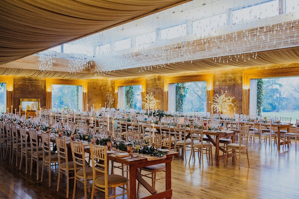 Candlelit wedding reception with long tables in twinkling venue